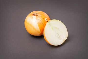 Two unpeeled whole and half raw yellow onions on black surface. Flat lay. Copy space