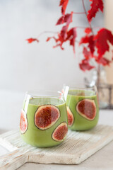 Delicious homemade Green matcha smoothie drink with bananas and figs in glasses. Side view, close up. Detox, superfood recipe, vegan menu, healthy food.