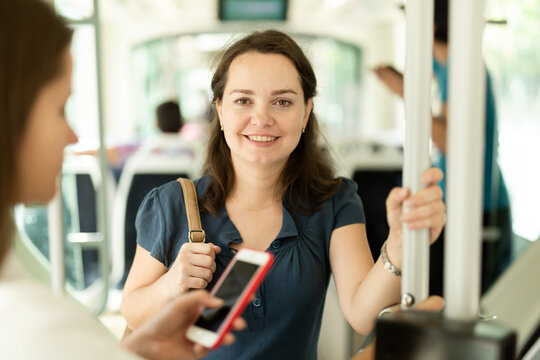 Portrait of cheerful woman passenger standing in public bus. High quality photo