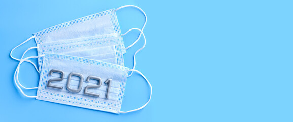 Three medical masks and numbers 2021 on a blue medical background. Concept of the protection against coronavirus, 2019-nCoV. Banner.