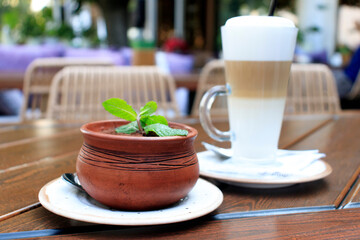 Coffee latte and tiramisu dessert on a wooden table in a cafe on the street close up