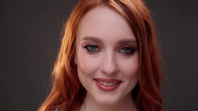 Red-haired woman 25-30 years old face close-up. Smile with teeth. Advertising of skin care products. Expression wrinkles. Shots under the eyes. Aging makeup.