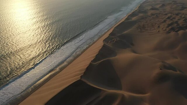 Aerial drone view of Namibian Atlantic coastline, road along the coast from Swakopmund to Walvis Bay, beach, surf break point, landscape with ocean background of sand dunes at Namibia's west coast