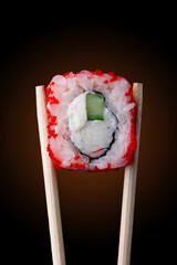 roll with salmon and sesame on chopstick on black background