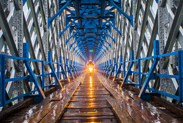 Fototapety  Most Cirahong w Tasikmalaya Regency w Indonezji, stary i unikalny most o konstrukcji stalowej i drewnianej. Pociągiem na górze i samochodem i motocyklem na moście