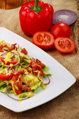 tomato vegetable salad with bacon and ingredients on wooden background