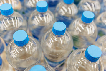 Rows of plastic water bottles with blue caps in a store. Top view.