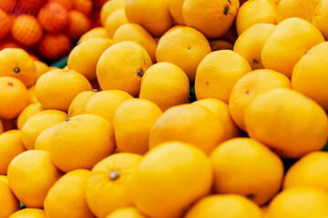 Lots of ripe tangerines on the counter in the store. Close-up.