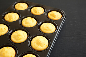 Homemade Cornbread Muffins on a black background, side view. Copy space.