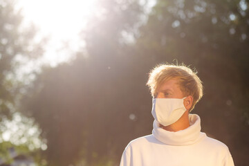 Portrait of a young man in a medical protective mask looking straight.