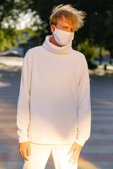 Portrait of a young man in a medical protective mask looking straight.