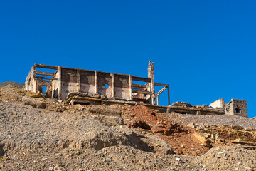 Obraz na płótnie Canvas An old abandoned factory in the mountains. Fragments of destroyed buildings. Mountains.Ruins of a poly metal factory.Abandoned industrial production.The ruins of a mining and processing plant.Blue sky