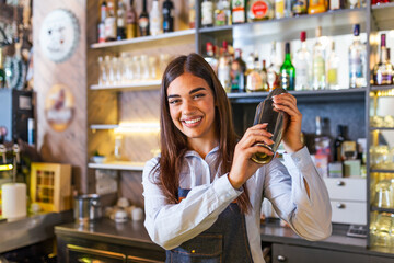 Young female worker at bartender desk in restaurant bar preparing coctail with shaker. beautiful young woman behind bar making coctail - obrazy, fototapety, plakaty