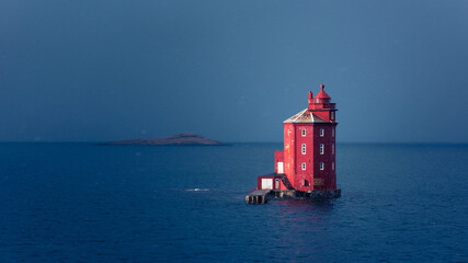 Famous red lighthouse  Kjeungskaer in the middle of the ocean near the Norwegian coast in snow storm