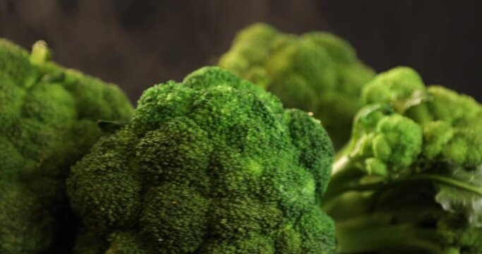 Green fresh broccoli with steam rotating at black background