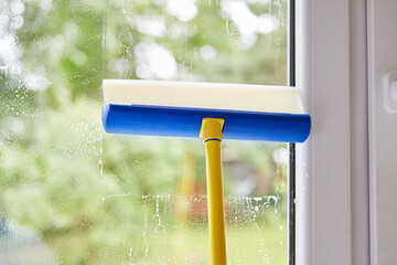 Fensterputzer reinigt Fenster mit Wischer