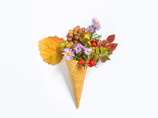 Ice cream cone with autumn leaves, rose hips and flowers. Grey background. Greeting card. Copy space, flat lay. Conceptual photo - gifts of autumn. Waffle cup with flowers.