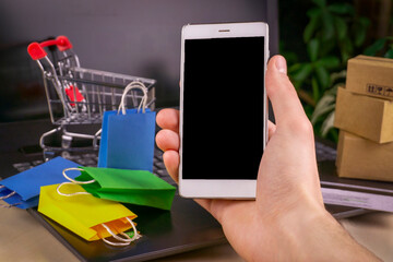 online shopping concept. little deliver boxes, smartphone, shopping bags, shopping bascket stand on laptop. copy space