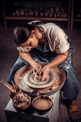Charming pottery master making ceramic pot on the pottery wheel . Ceramics art concept .