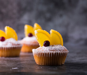 Cupcakes with slices of marmalade and cranberries on a gray background.