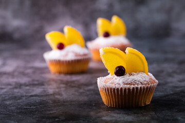 Cupcakes with slices of marmalade and cranberries on a gray background.