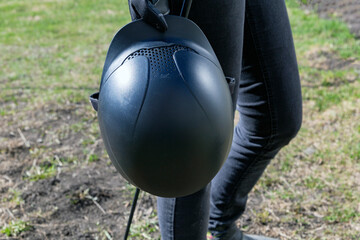 Woman in black gloves holding horse back riding helmet and whip in her hands. Equestrian equipment