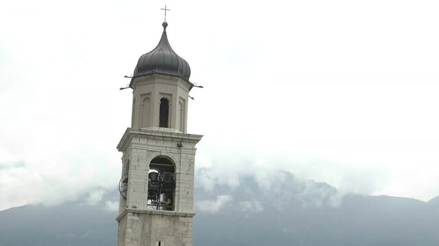 Handheld shot of church tower in a scenic location having it's bell toll for serious reason