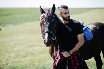 Obraz premium Arab tall beard man wear in black with arabian horse.