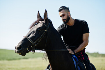 Obraz premium Arab tall beard man wear in black ride arabian horse.