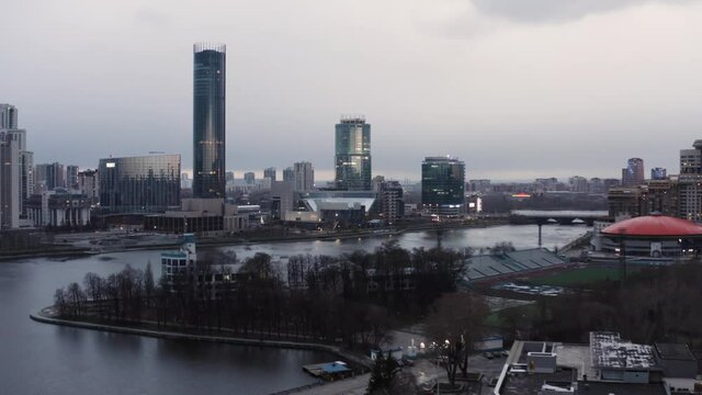 Panorama of the pond and Yekaterinburg Iset skyscraper. Stock footage. Aerial view of Dinamo building with round orange roof and the modern cityscape.