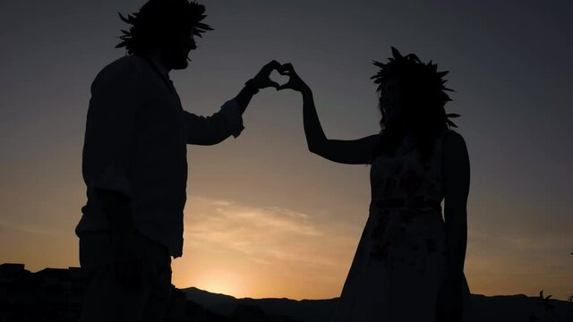 sagoma di un ragazzo e una ragazza con corona di alloro in testa che fanno il simbolo del cuore