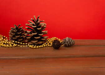 Cones with Christmas decorations on a wooden table and a red background. New Year mood
