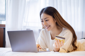 Asian woman buy items from the internet  with laptop by use credit card.