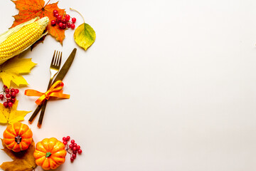 Thanksgiving place setting with cutlery and autumn leaves, top view