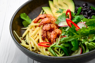 salad with avocado and shrimps in bowl, top view