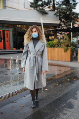 A young girl walks down the street wearing a protective medical mask. COVID-19 pandemic concept