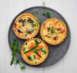 Tartlets with mushrooms, salmon and chicken on a wooden background.