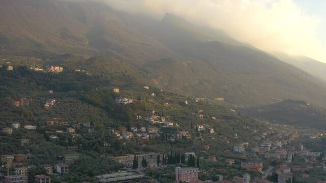 Aerial shot revealing Italian communities located up the mountains surrounding Lago Di Garda, Italy