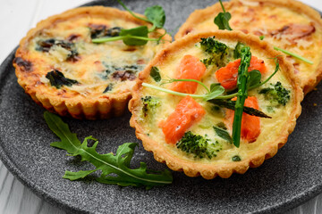 Tartlets with mushrooms, salmon and chicken on a wooden background.