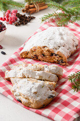 Fototapeta na wymiar Christmas cutted stollen with raisin and candied fruit on white background. Close up. Tasty traditional German bread.
