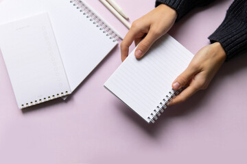 business composition with notebooks and pens on a pink background with a place to write. Business concept with hands holding notepad, writing text