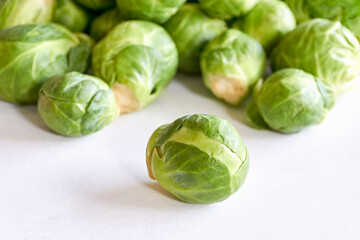 Closeup of green brussels sprouts with one in focus on white background. 