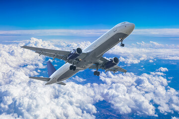 Obraz premium Commercial airplane flying above blue sky and white clouds.