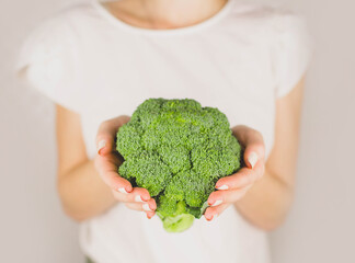 Fototapeta na wymiar girl holding green fresh broccoli in her hands on the white background