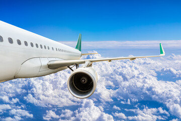 Commercial airplane flying above blue sky and white clouds.