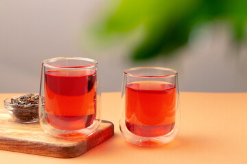 Two glass cups of black tea on beige table