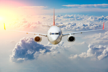 Fototapeta premium Commercial airplane flying above clouds in colorful sunset.Travel,holidays and business concept.