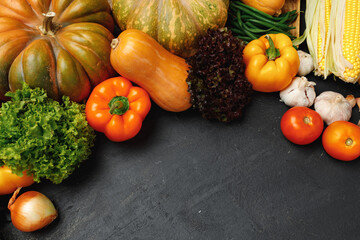Autumn vegetable composition with pumpkin, corn and pepper on black background