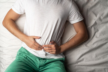 abdominal pain in an adult man. poisoning in a man. man holds his hands by the abdomen