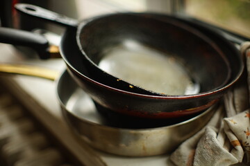 Set of old dirty pans and a towel on the windowsill.